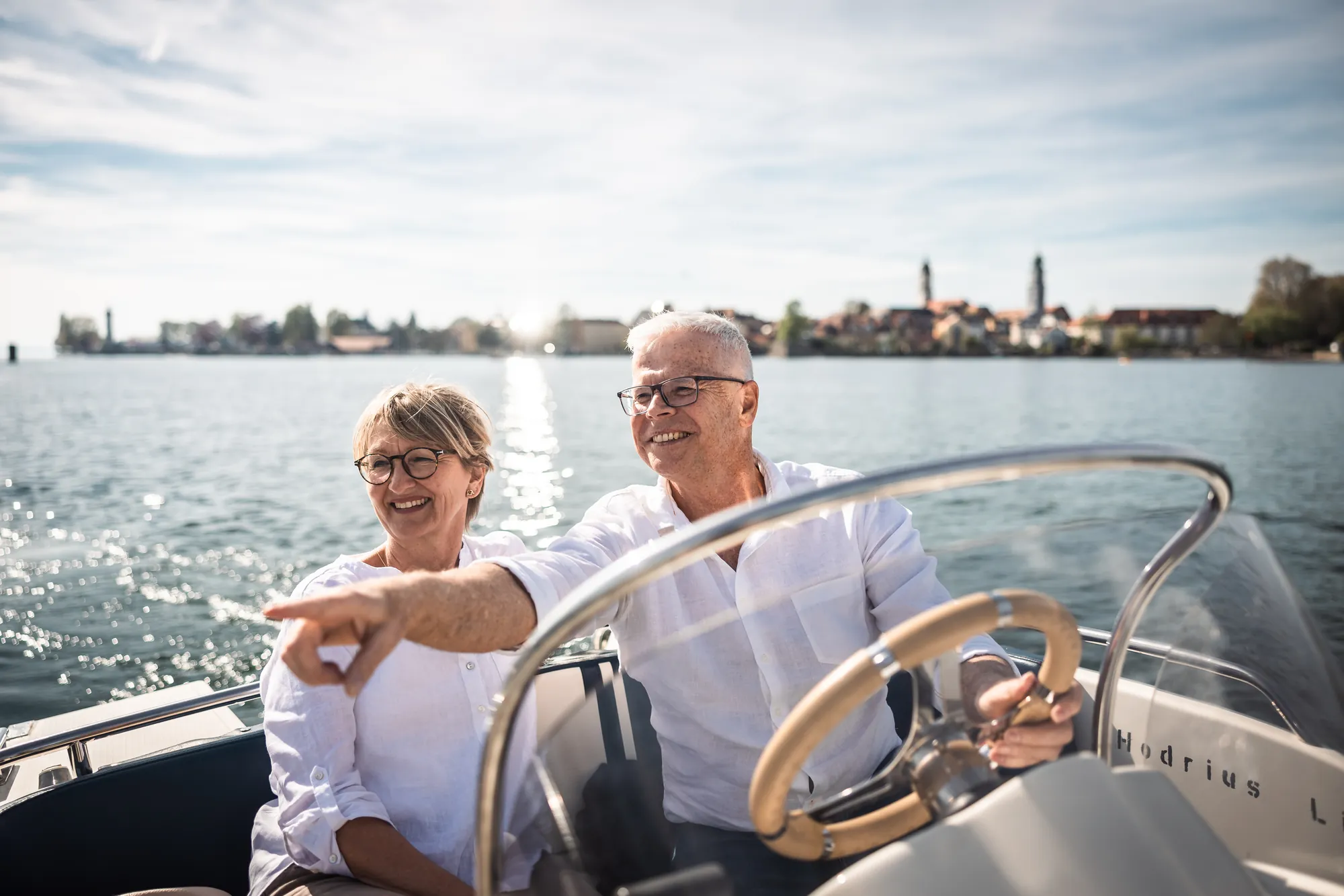 Älteres Paar fährt im Motorboot über den Bodensee, am Horizont die Lindauer Insel.