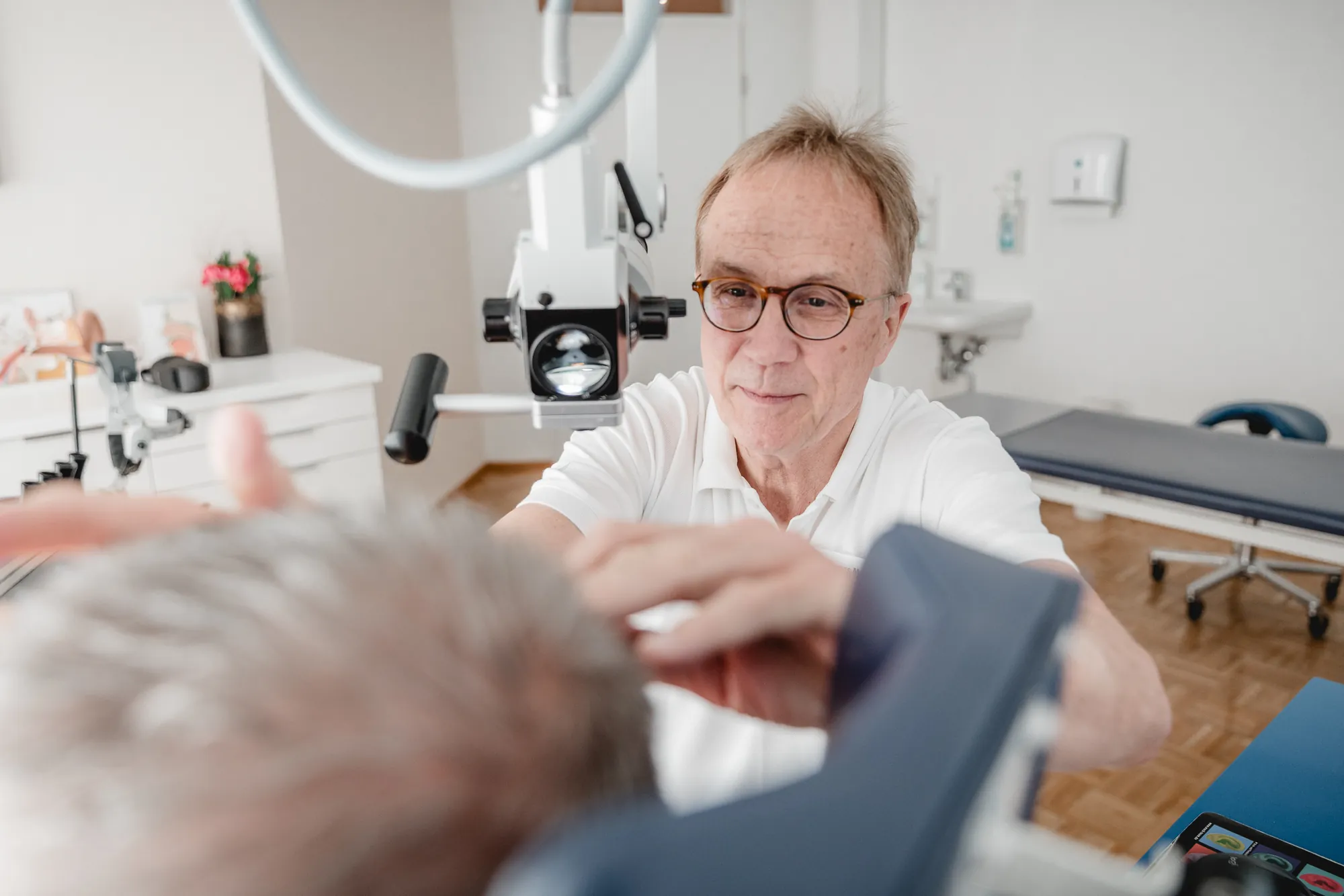 Arzt untersucht einen Patienten am Untersuchungsmikroskop.