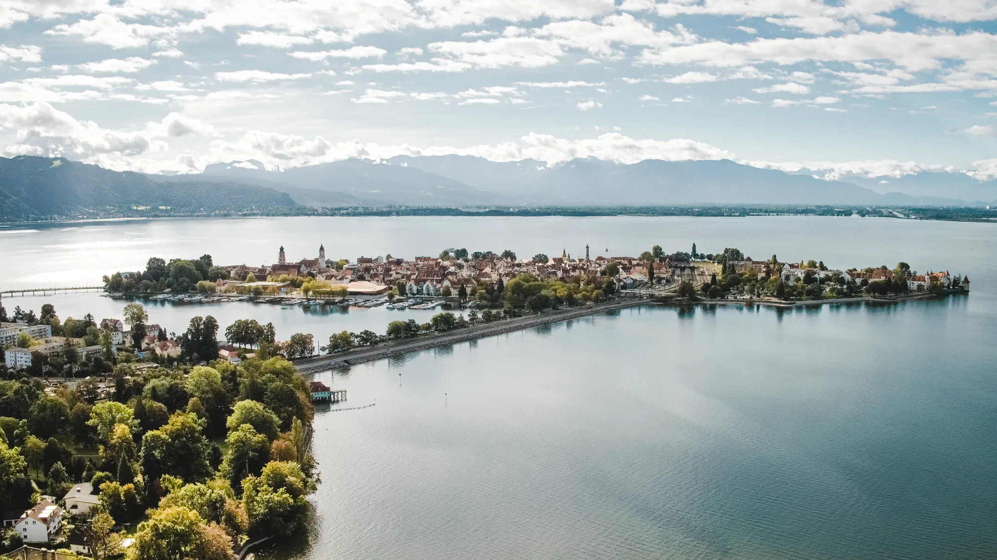 Luftbild der Lindauer Insel im Bodensee, dahinter die Alpenkette.