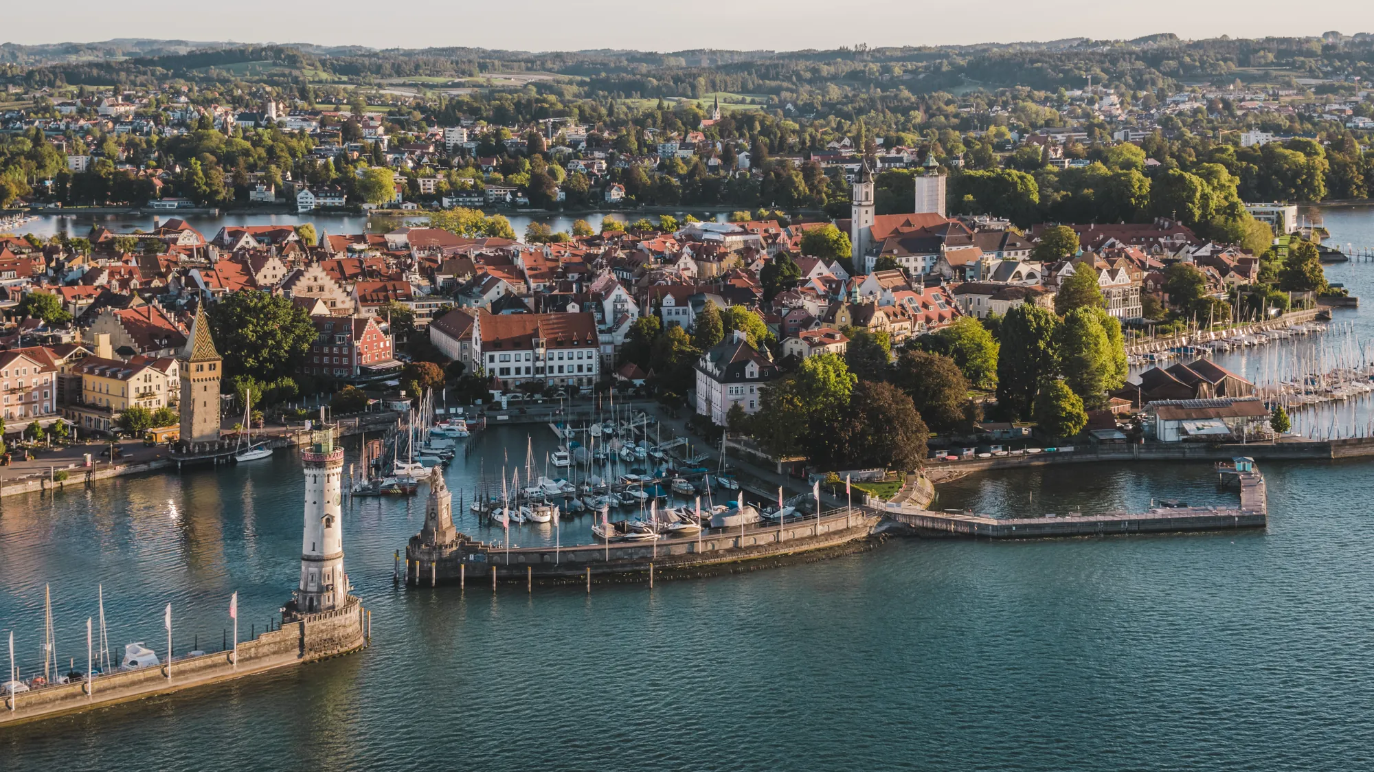 Luftaufnahme der Lindauer Insel mit Hafeneinfahrt und Leuchtturm im Morgenlicht.