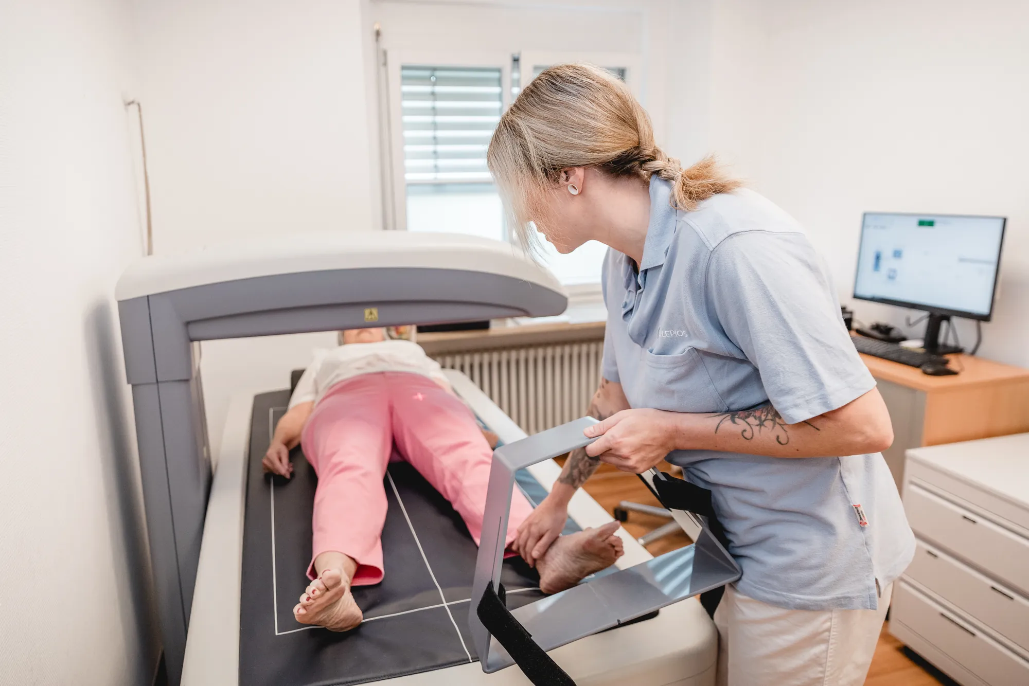 MFA positioniert eine liegende Patientin an einem Untersuchungsgerät.